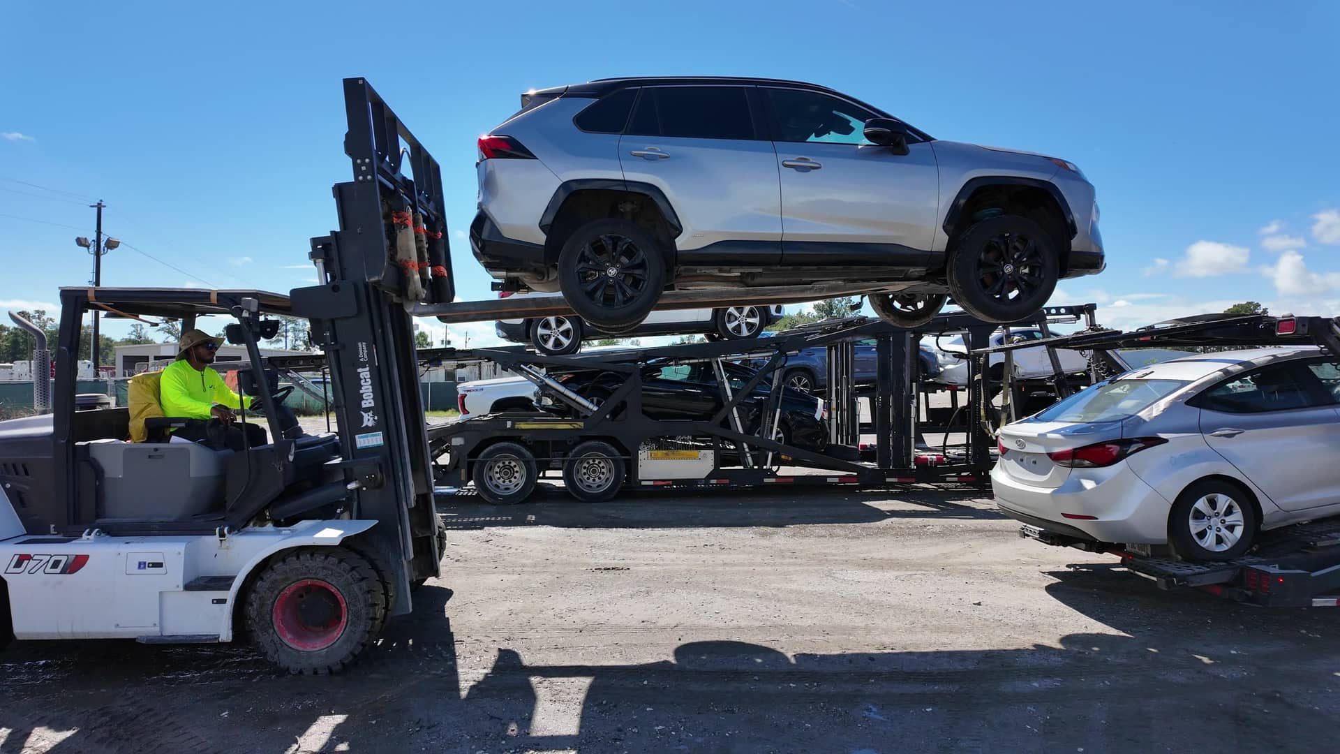 Forklift carrying an SUV from a car carrier at the Jax Auto Shipping yard in Savannah